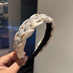 Détail du serre-tête tressé beige avec rubans de satin et fils métalliques brillants