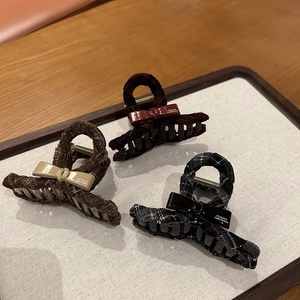 Detailed view of elegant bow hair claws in dark coffee, burgundy, and plaid fabric