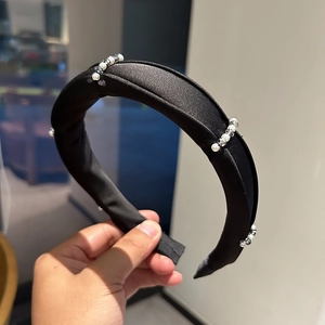 Detailed cluster of white pearls and faceted grey crystals on a padded black satin headband