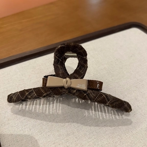 Detail of a brown plaid hair claw clip featuring a handmade bow and resin teeth