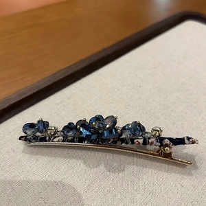 Detailed macro view of handmade blue crystal spring hair clip with woven fabric base