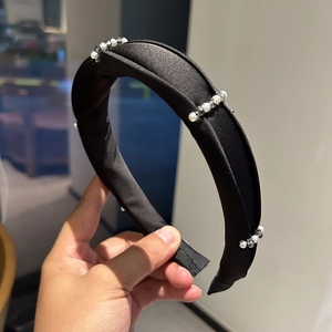 Detailed close-up of crystal pearl embellishments on a black padded velvet headband