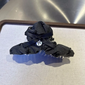 Detail of grey denim hair claw clip with black bow patterns and silver metal tag