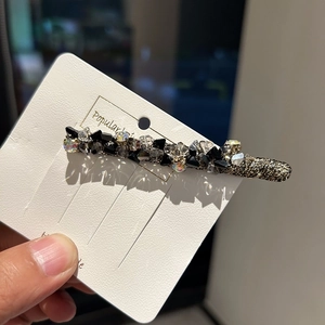 Barrette à cheveux étincelante avec cristaux noirs et irisés sur une carte de présentation
