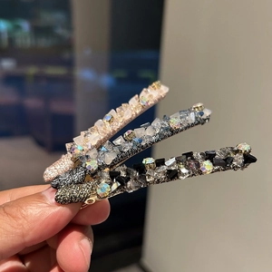Close-up of three crystal hair clips in gold, silver, and black metal finishes