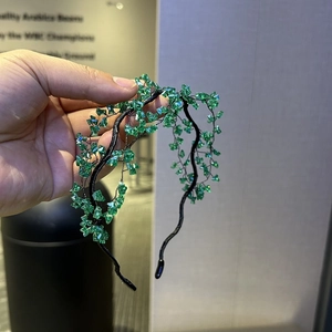 Detail of handmade green crystal beaded headband with wire wrapping on a black metal base