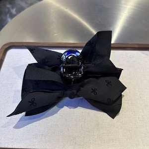 Detail of black bow hair claw clip featuring textured fabric and multi-layered design