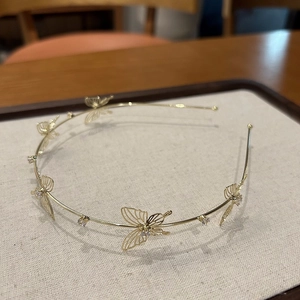 Detailed close-up of a gold metal headband featuring hollow butterflies and rhinestones