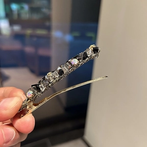 Détail d'une barrette dorée ornée de cristaux noirs et brillants en gros plan