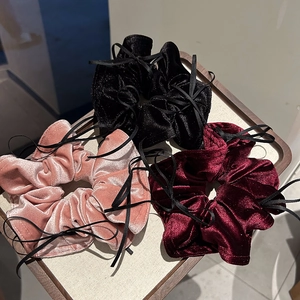 Detailaufnahme von Samt-Haargummis mit Schleifen in Schwarz, Rosa und Weinrot