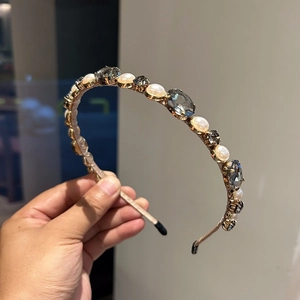 Close-up of luxury headband with grey crystals and white pearls on gold metal base