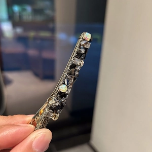 Détail de la barrette à cheveux dorée ornée de strass en cristal noir et gris