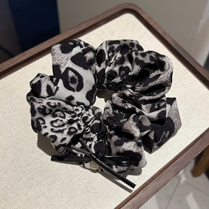 Détail de chouchou imprimé léopard avec nœud noir sur un plateau en lin élégant