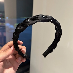 Dettaglio del cerchietto intrecciato nero con strass argentati e denti a pettine