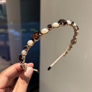 Detail of beaded headband with purple rhinestones, brown gems and white pearls