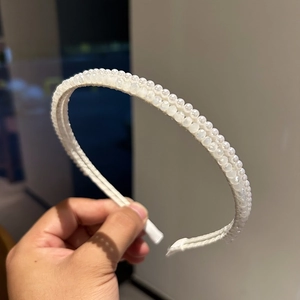 Dettaglio dell'elegante cerchietto con doppie file di perle bianche lucide e design chic
