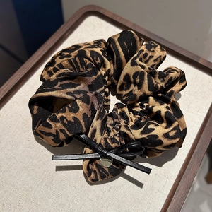 Chouchou léopard avec nœud noir et médaille dorée pour coiffure queue de cheval haute