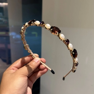 Detail of white faux pearls and amber rhinestones on a gold metal headband