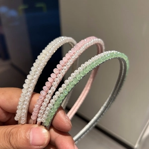Primo piano di tre eleganti cerchietti di perline nei colori bianco crema, rosa e verde chiaro