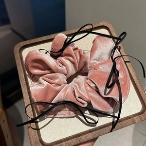Eleganter Samt-Haargummi in Altrosa mit schwarzer Schleife auf einem Display-Tablett