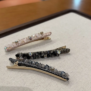 Détail de trois barrettes à cheveux en cristal scintillant avec base en métal sur gris