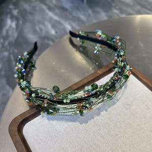 Detail of green beaded headband with colorful crystal pearls on a luxury display tray