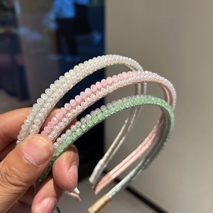 Dettaglio macro di tre cerchietti con perle e cristalli in crema, rosa e verde pastello