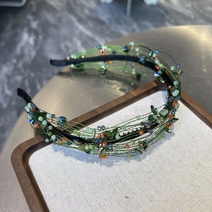 Detail of hand-woven green headband with colorful faceted crystal beads on display