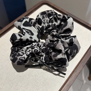 Détail du chouchou léopard avec un nœud noir et une boucle en métal doré élégante