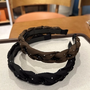 Dettaglio di cerchietti intrecciati con strass discreti e perline nere su tessuto