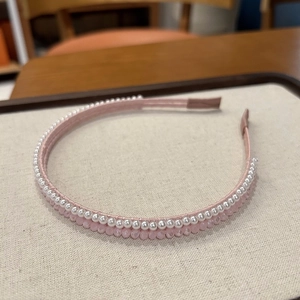 Dettaglio del cerchietto in raso rosa con file di perle bianche e perline di cristallo