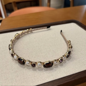 Detailed macro view of vintage hairband with pearls and deep red burgundy gems