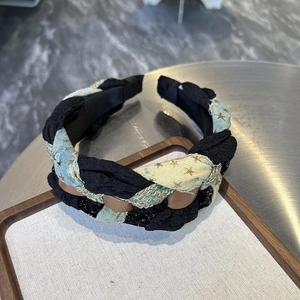 Close-up of woven denim headband with star patterns in a wooden tray on a desk