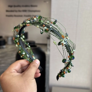 Detailed close-up of a woven green headband featuring colorful crystal beads and sequins