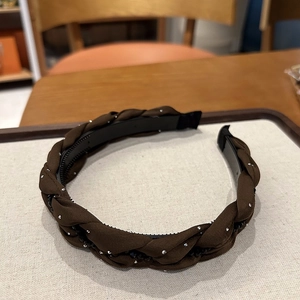 Dettaglio di cerchietto intrecciato marrone con strass e denti interni antiscivolo chic