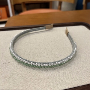 Dettaglio del cerchietto in tessuto grigio con perle bianche e cristalli verdi sfaccettati
