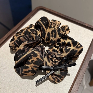Vue détaillée du chouchou léopard avec nœud en cuir et pendentif doré raffiné