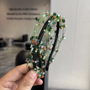 Handmade woven headband with green and orange faceted crystal beads in a knotted forest style