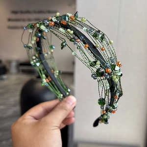 Detail of handwoven green wire headband with colorful crystal beads and layered craftsmanship