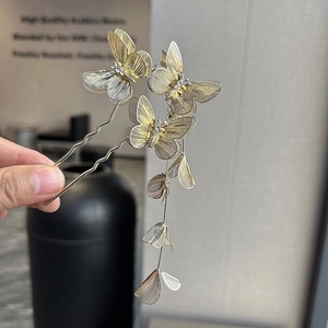 Detail of golden butterfly hair pins with hollow brushed texture and elegant tassels