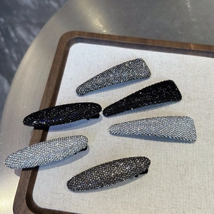 Set of six sparkling rhinestone hair clips in silver, grey and black on a wooden tray