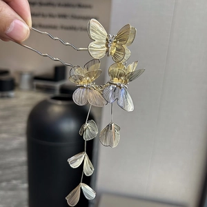 Detail of golden U-shaped hair stick with 3D butterflies, tassels and white rhinestones