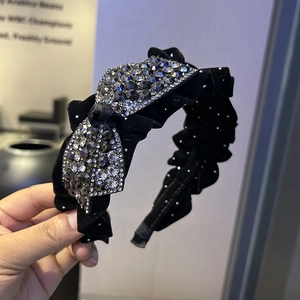 Détail d'un serre-tête en velours noir avec des nœuds en strass et des bords plissés