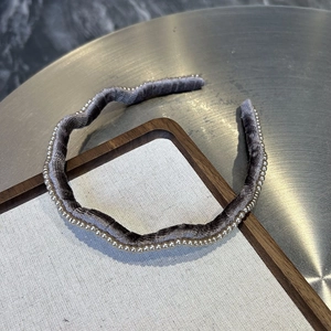 Détail d'un serre-tête en velours gris ondulé orné de petites perles blanches élégantes