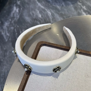 Detailed close-up of a padded beige satin headband with pearl and camellia charms