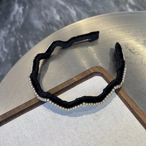 Détail d'un serre-tête en velours noir ondulé avec des perles élégantes sur le tissu