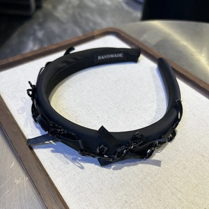 Detailed view of handmade black fabric headband with beadwork and velvet ribbon textures