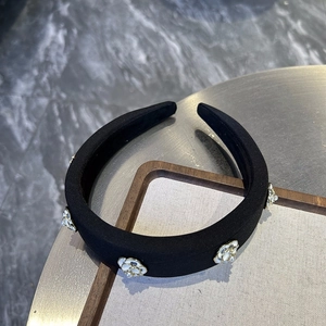 Close-up of elegant black velvet padded headband with white camellia and pearl details