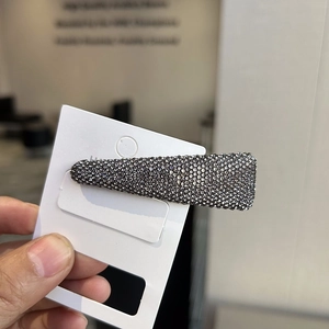 Detailed macro view of trapezoid hair clip with grey rhinestones on a card