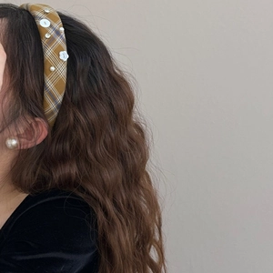 Gros plan d'un serre-tête vintage à carreaux jaunes avec perles et boutons floraux